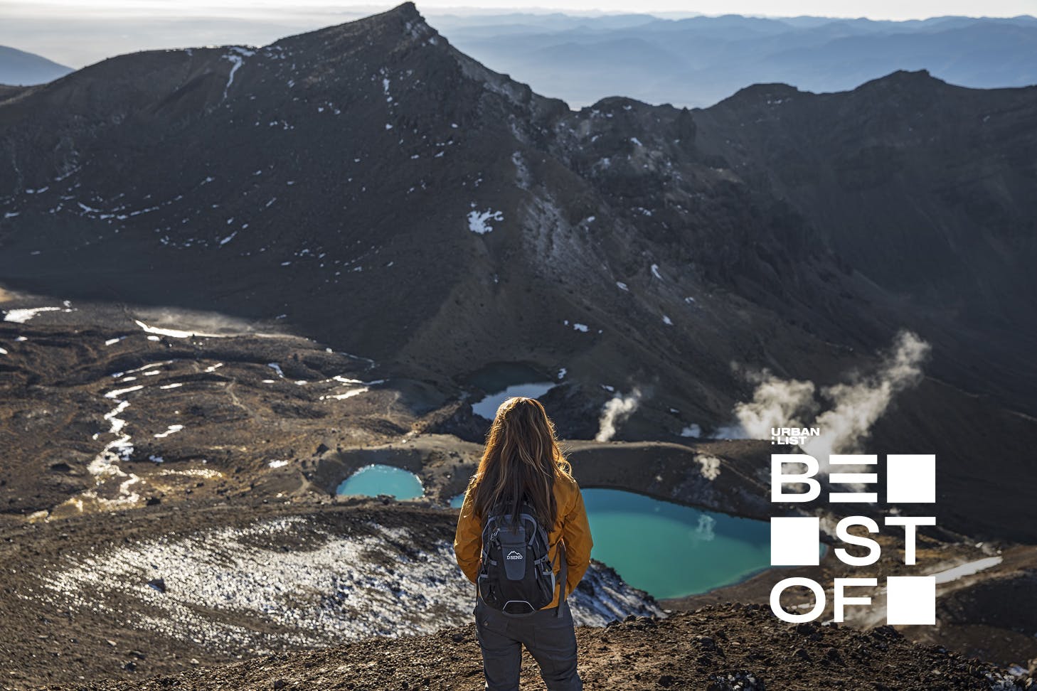 A walker looks out at a green lake on the Tongariro Crossing, Ruapehu